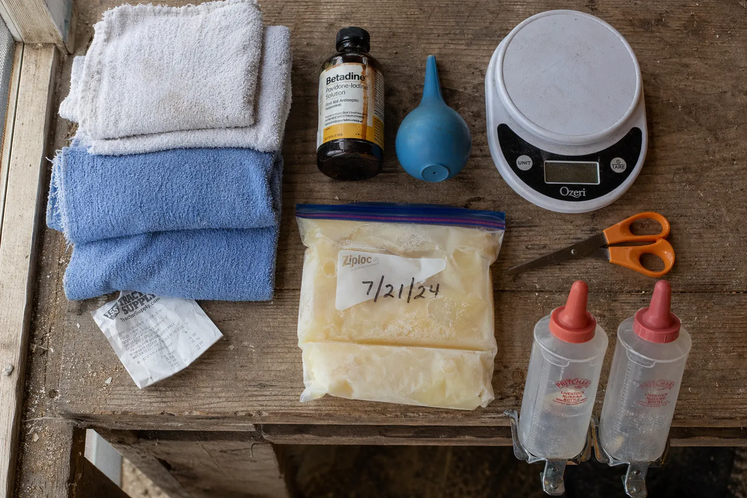 Organized kidding kit with bottles, towels, scale, and supplies laid out on a barn shelf