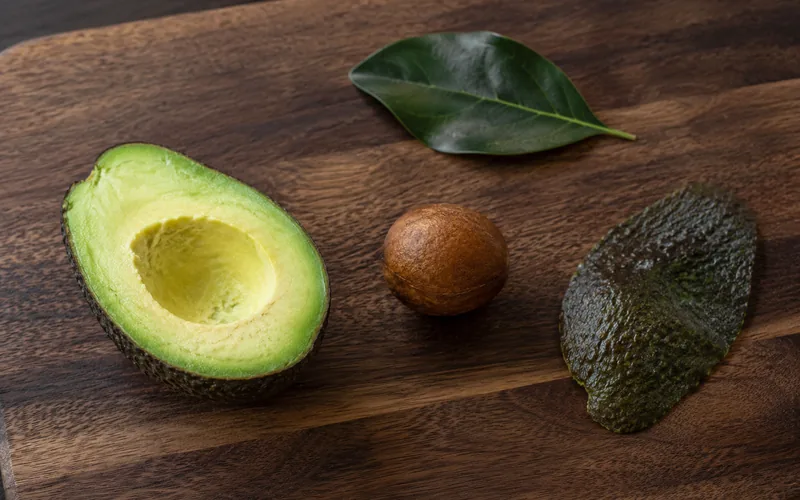 The leaves, pit, skin, and flesh of an avocado laid out to show the toxic parts