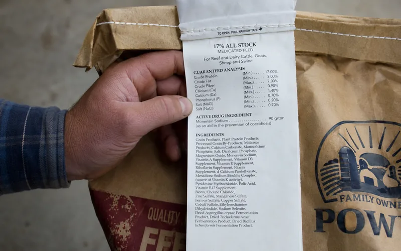 Hand holding a feed bag tag showing the guaranteed analysis panel