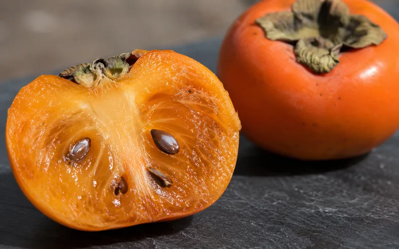 Cross-section of a ripe persimmon showing the deep orange, jelly-like flesh and seeds