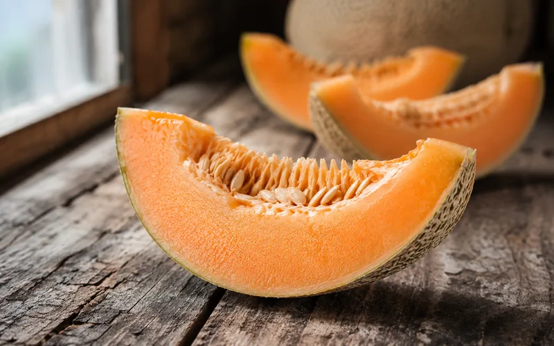 Sliced cantaloupe showing orange flesh and netted rind