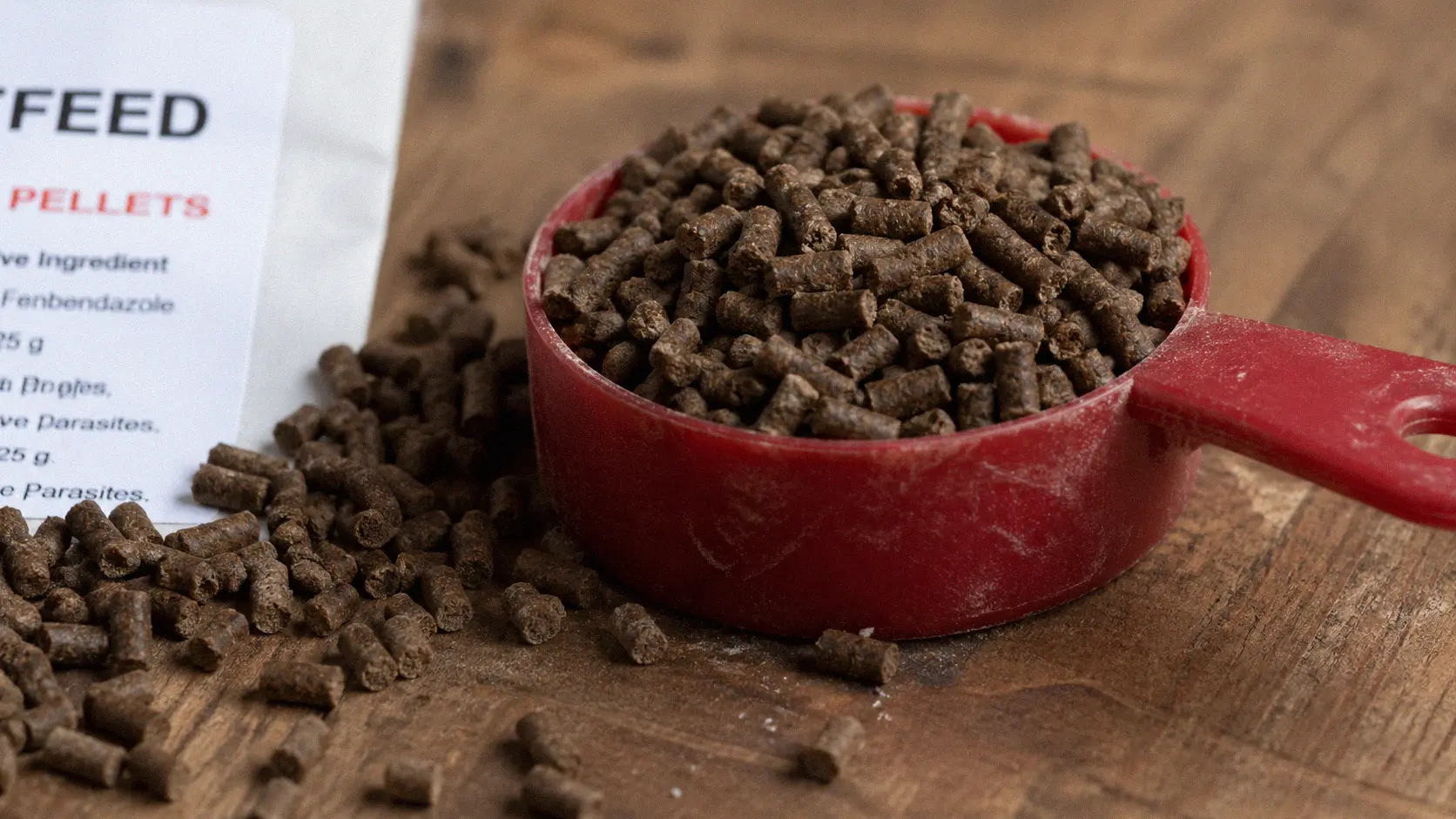 Close-up of medicated dewormer pellets next to a measuring scoop