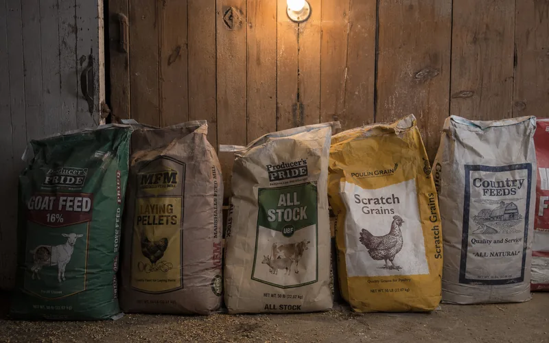 Assorted feed bags stacked in a farm storage room
