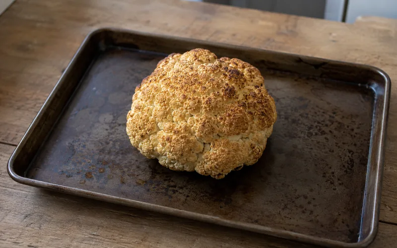 Plain roasted cauliflower florets spread on a metal baking tray with no seasoning